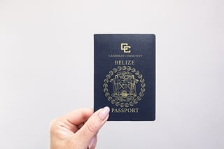 Close Up Of A Belize Passport Held In Hand Against A Plain White Background