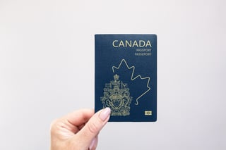 Close-up of a Canada-held passport in hand against a plain white background