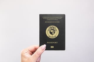 Close up of a Guinea passport held in hand against a plain white background