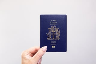 the close-up of a iceland passport held in hand against a plain white background