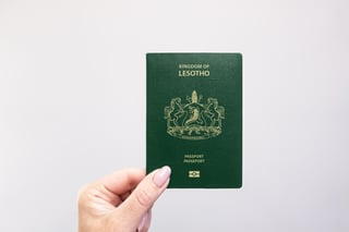 Close Up Of A Lesotho Passport Held In Hand Against A Plain White Background