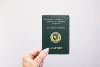 Gros plan d'un passeport libérien tenu à la main sur un fond blanc uni