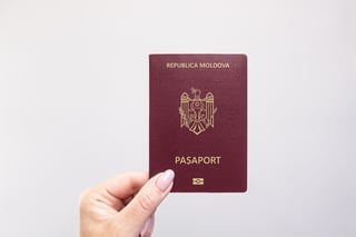 Close Up Of A Moldova Passport Held In Hand Against A Plain White Background