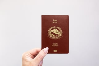 Close-up of a Nepal-held passport in hand against a plain white background