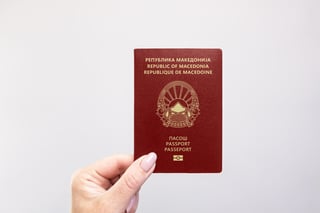 Close Up Of A North Macedonia Passport Held In Hand Against A Plain White Background