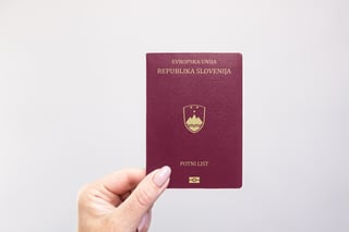 Close Up Of A Slovenia Passport Held In Hand Against A Plain White Background