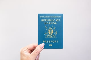 Close Up Of A Uganda Passport Held In Hand Against A Plain White Background