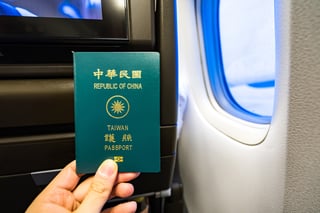 Closeup Of Man Holding Taiwan Passport And Boarding Pass At Airplane