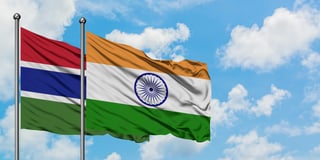Drapeaux de la Gambie et de l'Inde flottant ensemble dans le vent sous un ciel bleu nuageux, symbole de diplomatie