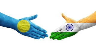 Poignée de main entre les drapeaux de l'Inde et des Palaos peints sur des mains, image isolée sur fond transparent