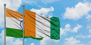 India and cote d ivoire flag waving in the wind against white cloudy blue sky together
