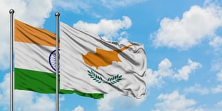 India and cyprus flag waving in the wind against white cloudy blue sky together