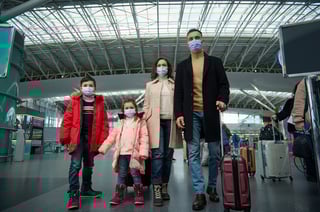 multiracial young happy family at the airport with luggage while waiting for a flight in a pandemic