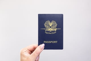 Papua New Guinea Passport Held In Hand Against A Plain White