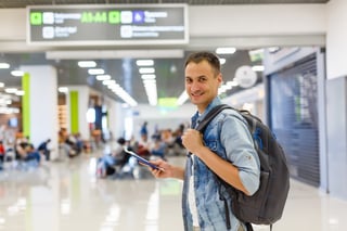 Portrait of a happy male traveler walking with backpack
