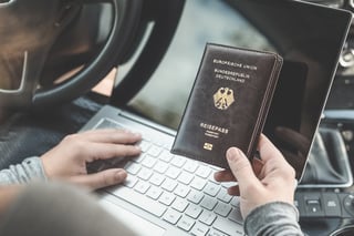 Woman in the car with laptop and germany passport travel concept