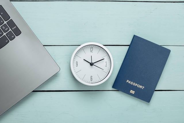 Laptop A Clock And A Passport On A Table