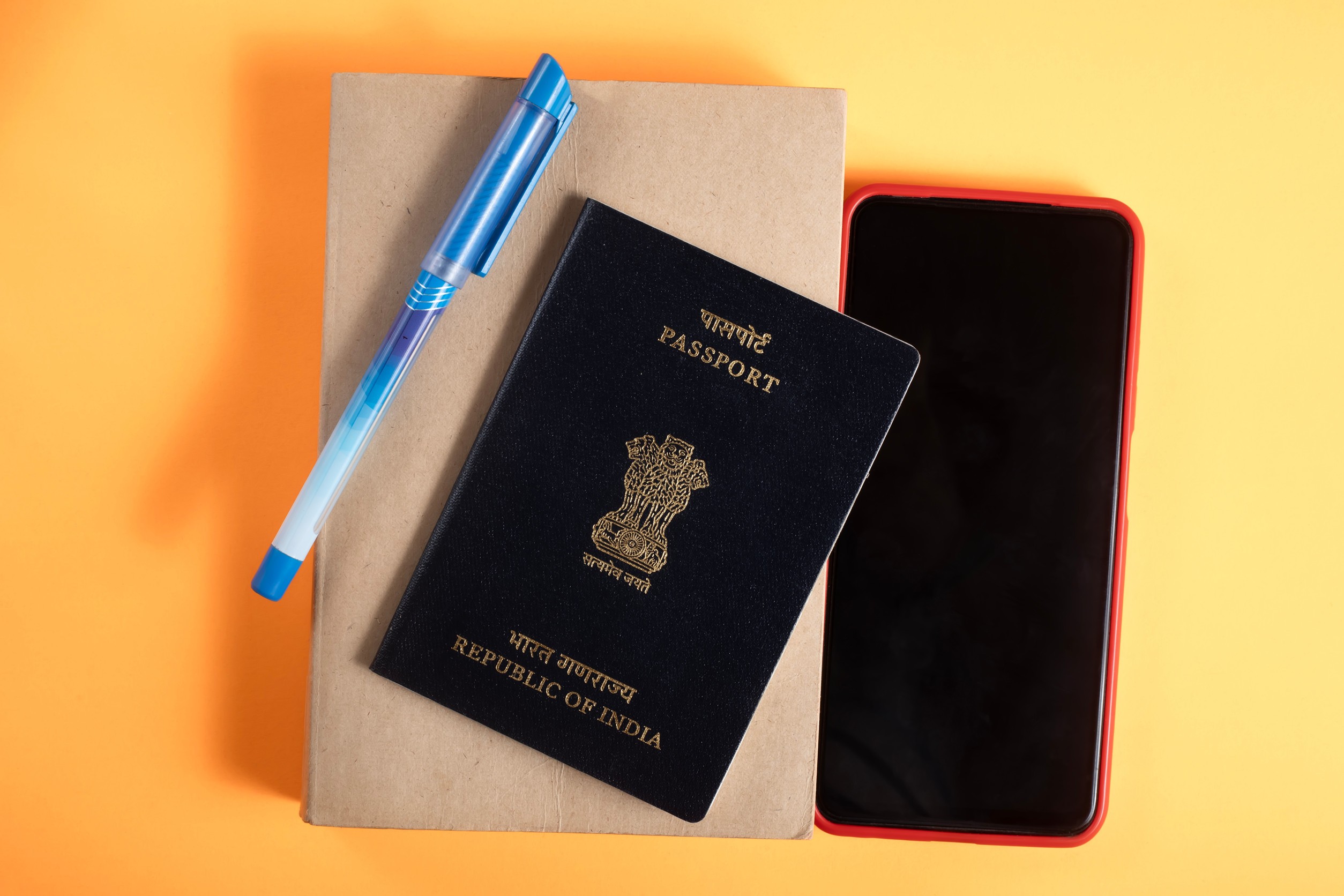 Nahaufnahme eines indischen Reisepasses, Stifts, Notizbuchs und Telefons
