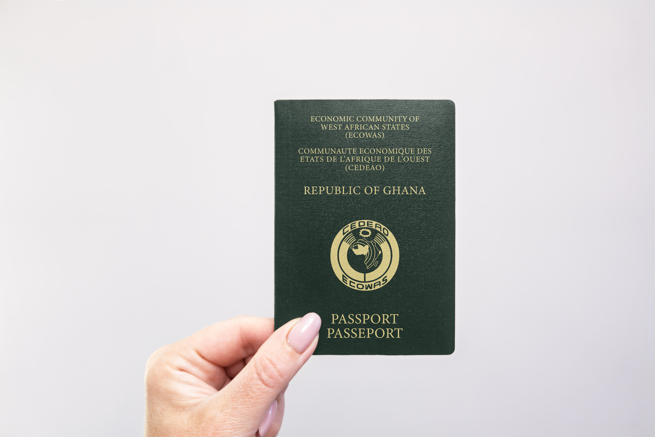 Nahaufnahme eines ghanaischen Reisepasses, der in der Hand vor weißem Hintergrund gehalten wird