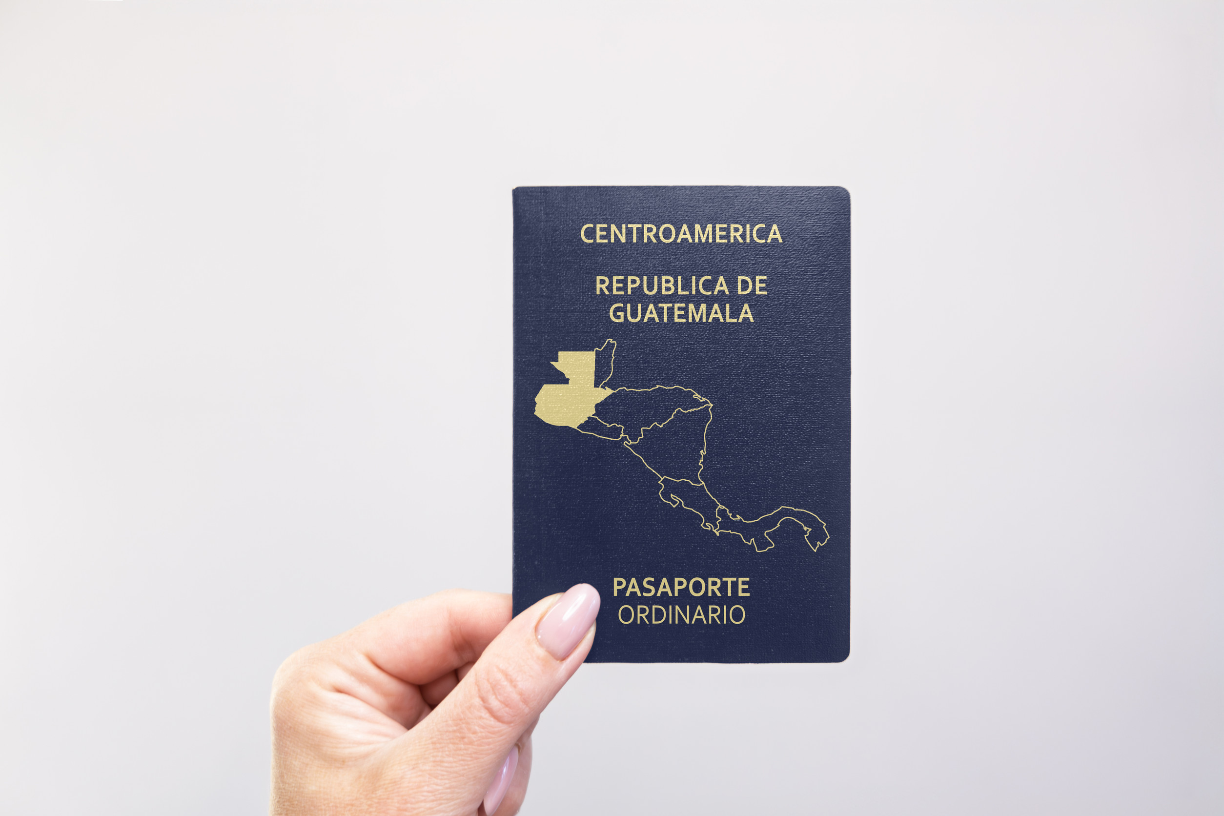 Nahaufnahme eines guatemaltekischen Reisepasses, der in der Hand vor weißem Hintergrund gehalten wird