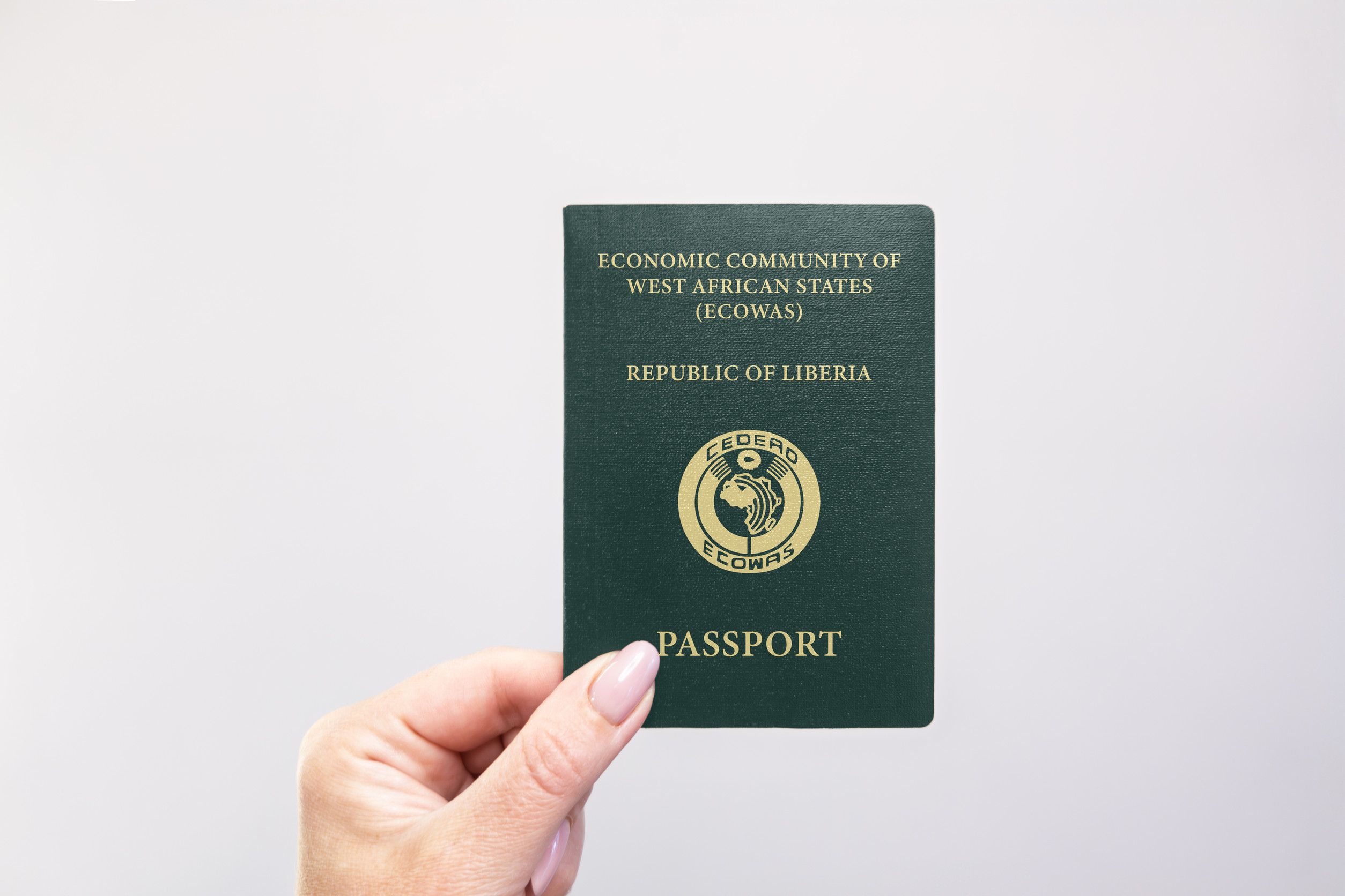 Nahaufnahme eines liberianischen Reisepasses, der in der Hand vor weißem Hintergrund gehalten wird
