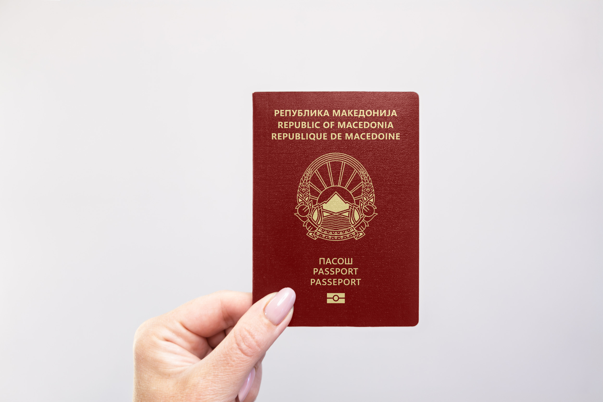 Nahaufnahme eines nordmazedonischen Reisepasses, der in der Hand vor weißem Hintergrund gehalten wird