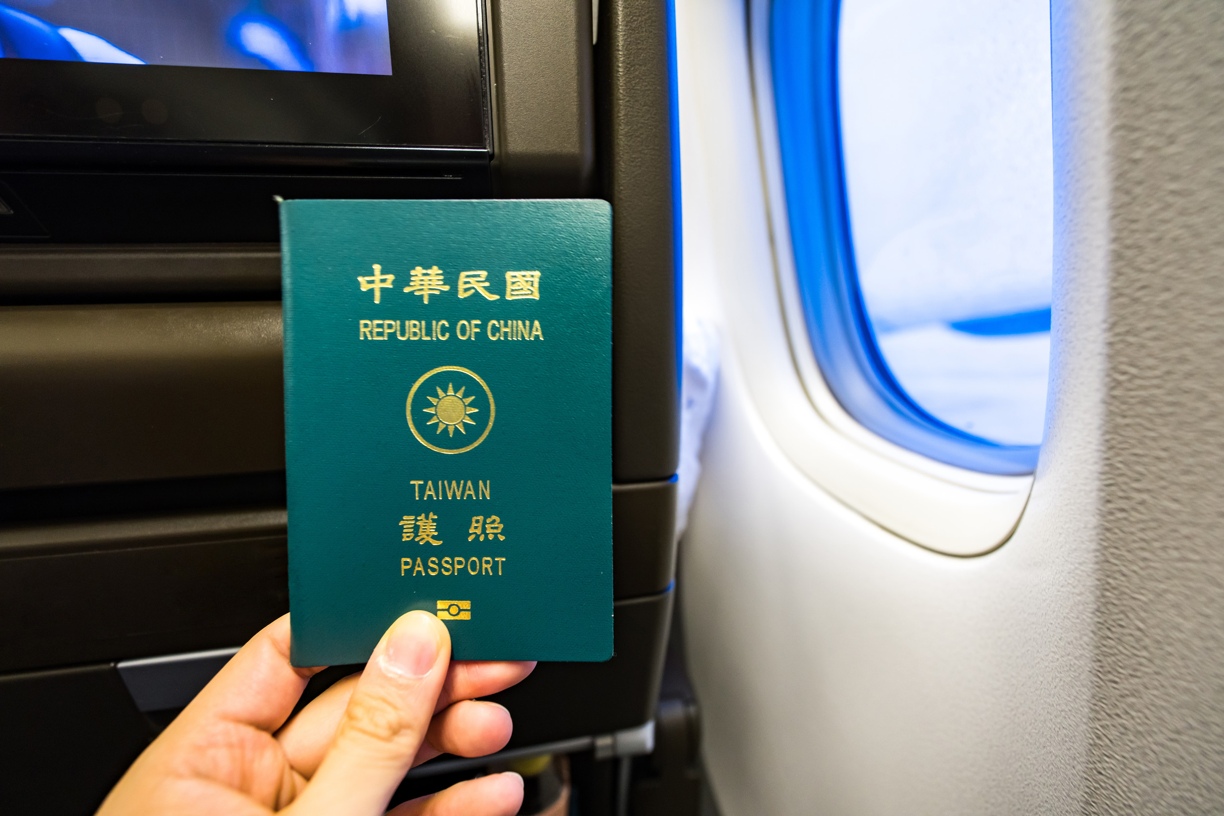 Nahaufnahme eines Mannes, der einen taiwanesischen Reisepass und eine Bordkarte im Flugzeug hält