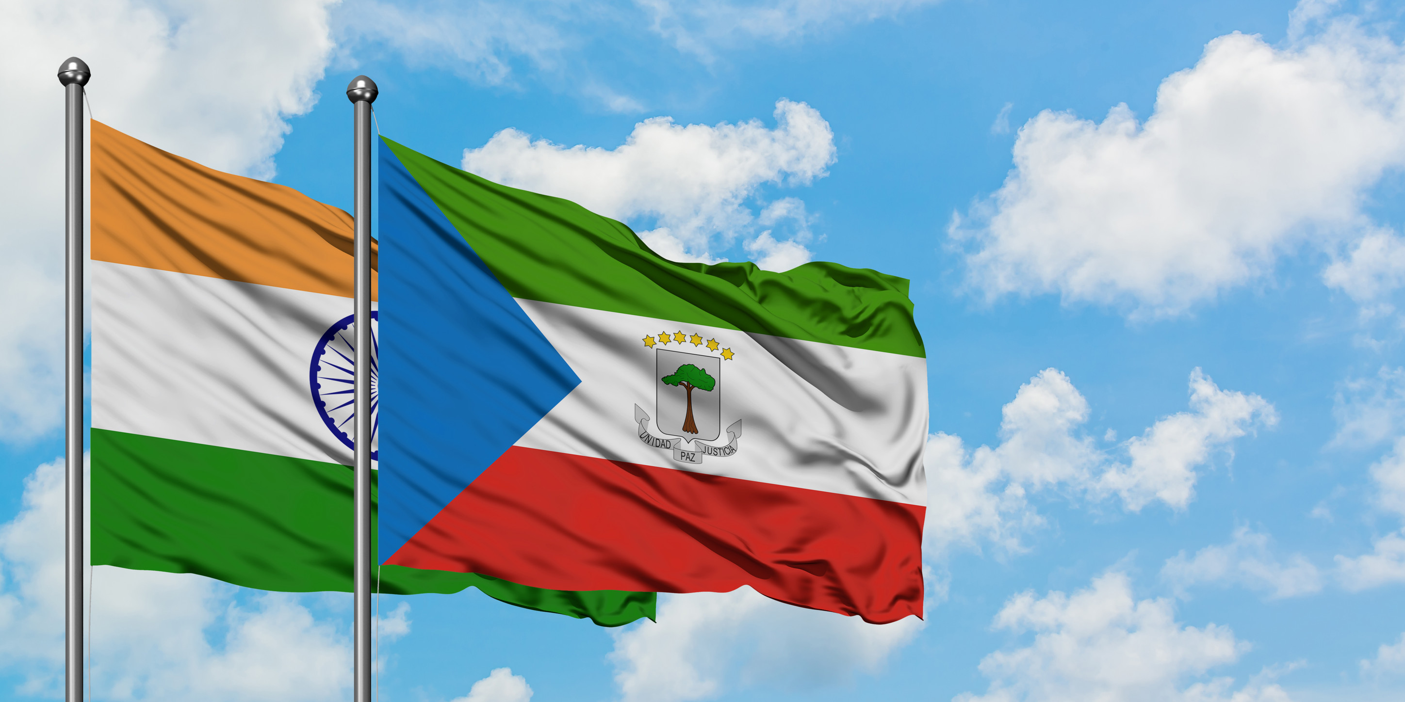 Indische und Äquatorialguinea-Flagge wehen im Wind vor bewölktem, blauem Himmel
