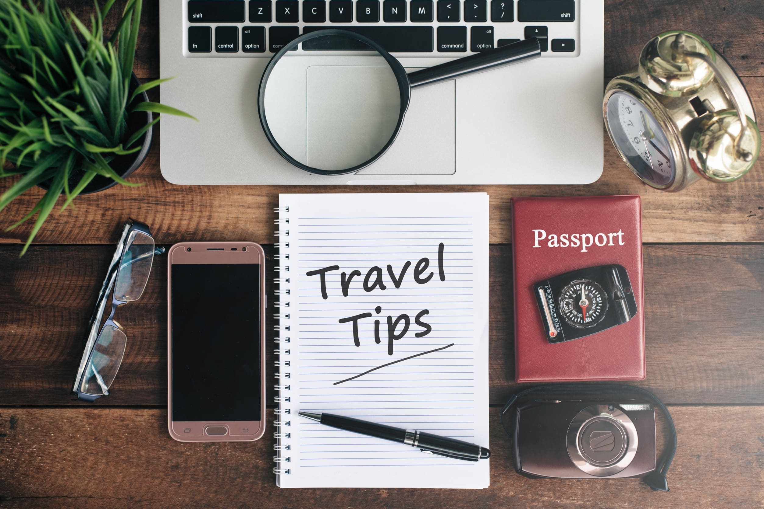 Laptop, Notizbuch, Smartphone, Reisepass, Kompass, Lupe und Uhr mit dem Wort Reisetipps