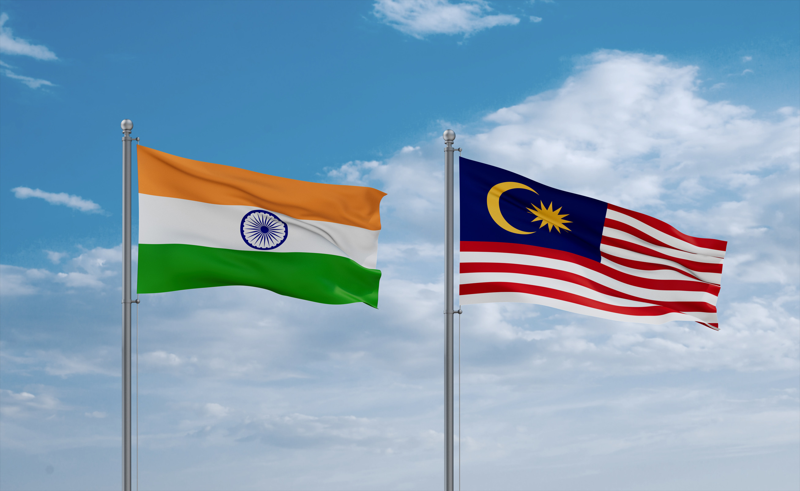 Malaysia und Indien Flaggen wehen zusammen im Wind vor blauem, wolkigem Himmel
