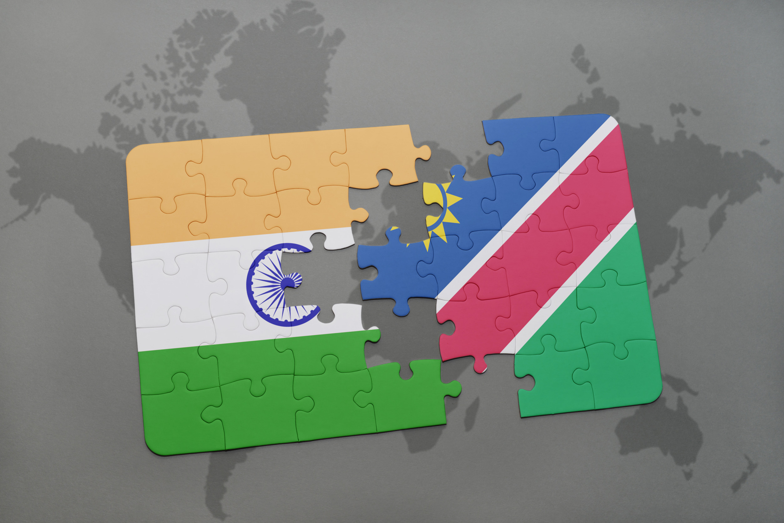 Puzzle mit der Nationalflagge von Indien und Namibia auf einer Weltkarte